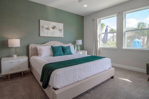 A bedroom with a bed, two bedside tables, a nightstand, a window, and a painting on the wall. - 6BR near Disney | Pool, spa & 2 game rooms (Kissimmee)