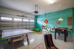 A room with a ping pong table, a foosball table, and a dartboard on teal walls. - 6BR near Disney | Pool, spa & 2 game rooms (Kissimmee)
