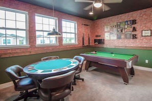 A room with a pool table, chairs, and a brick wall with various signs. - 6BR near Disney | Pool, spa & 2 game rooms (Kissimmee)