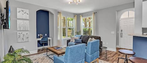 A modern living room with a sofa, coffee table, and a TV mounted on the wall.