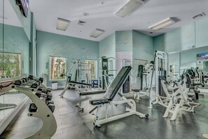 A gym with various exercise equipment, large windows, and a view of greenery outside. - 2BR condo near Disney | Resort with pool (Kissimmee)