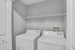 A laundry room with two stacked washing machines and a drying rack. - 2BR condo near Disney | Resort with pool (Kissimmee)
