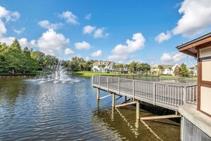 A waterfront property with a dock, a fountain, and residential buildings in the background. - 2BR condo near Disney | Resort with pool (Kissimmee)