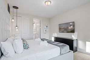 A hotel room with a bed, a fireplace, a painting, and a television. - 11BR near Disney | Pool, spa & home theater (Kissimmee)