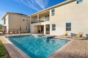 A two-story building with a swimming pool, outdoor seating, and a covered patio area. - 11BR near Disney | Pool, spa & home theater (Kissimmee)