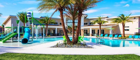 A pool area with a water slide, palm trees, and lounge chairs.