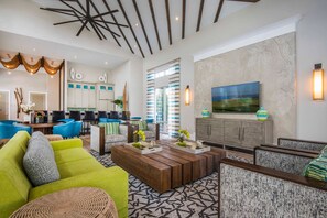 A modern hotel lobby with a seating area, a kitchen in the background, and a large window with curtains. - 8BR near Disney | Private pool, spa & game room (Kissimmee)