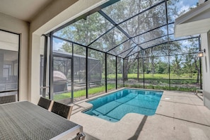 Ein überdachter Außenpool mit Glasveranda, umgeben von einer Terrasse mit Tisch und Stühlen.