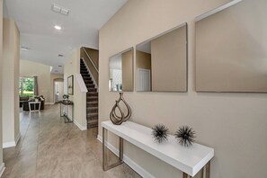 Ein modernes Interieur mit einer Treppe, einem Konsolentisch mit Dekoration und einem Flur, der in einen anderen Raum führt.