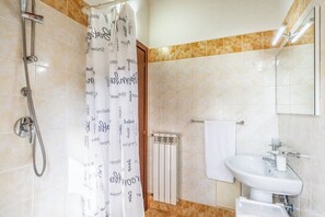 Une salle de bain avec une douche, un lavabo et un porte-serviettes.