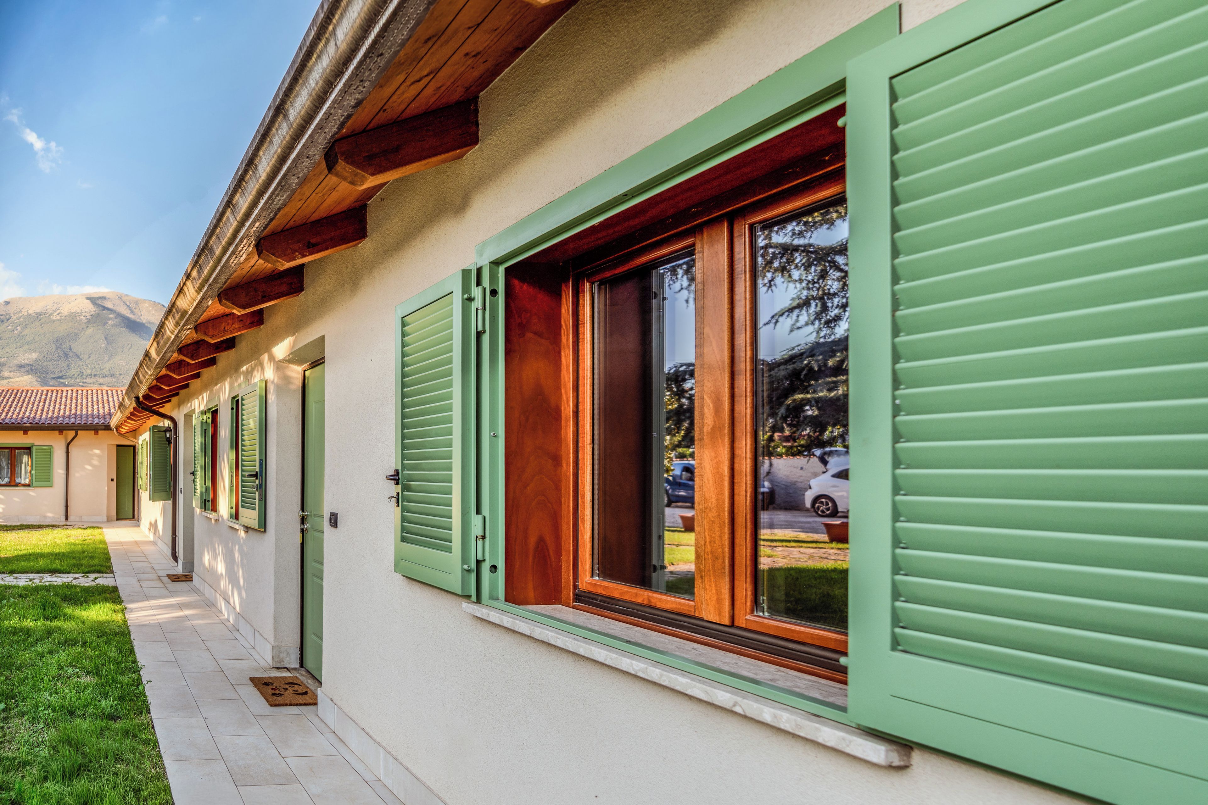 A building with green shutters, a tiled roof, and a clear sky.