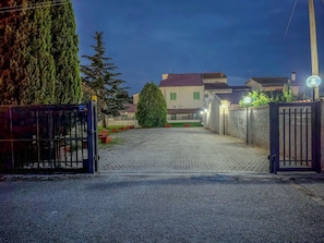 Un camino pavimentado que conduce a una entrada con puerta y un edificio al fondo.