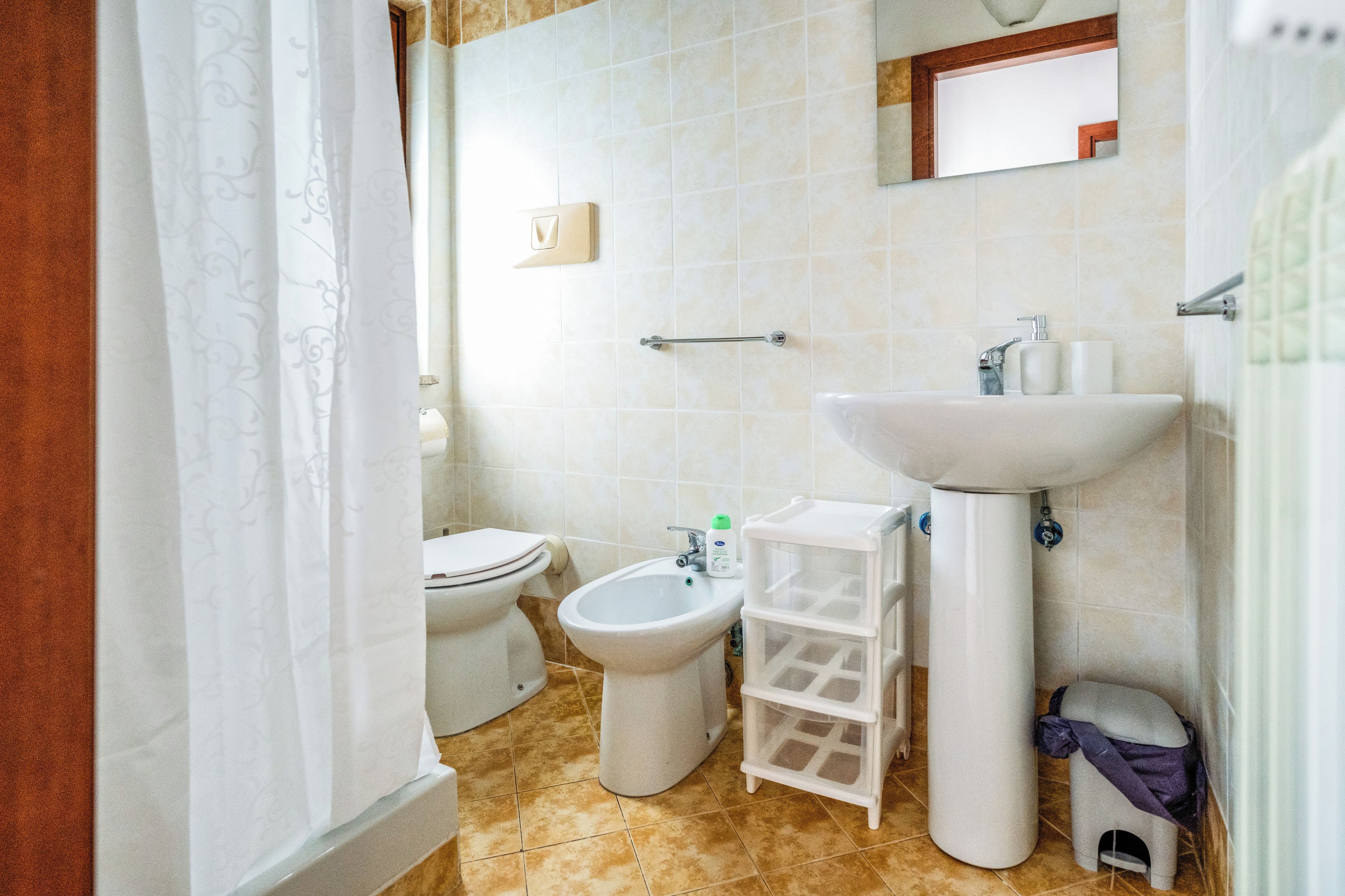 Een badkamer met toilet, wastafel, spiegel en bidet.