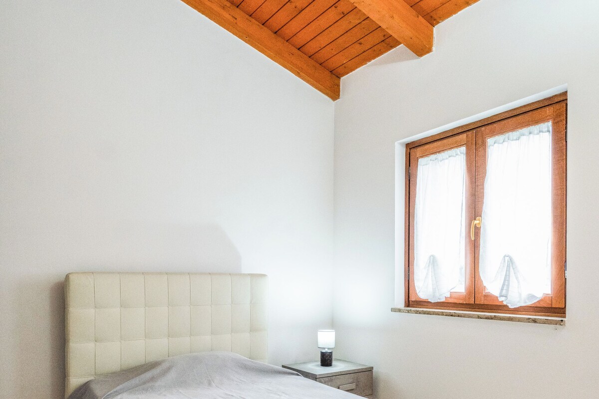 Une chambre à coucher avec un lit, une table de chevet, une fenêtre et un plafond en bois.