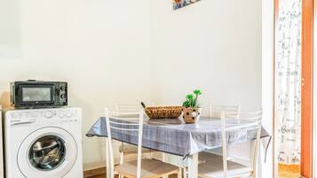 Ein Essbereich mit einem Tisch für vier Personen, einer Waschmaschine und einem Bild an der Wand.