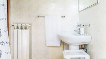 A bathroom with a white sink, a mirror, a towel rack, and a radiator.