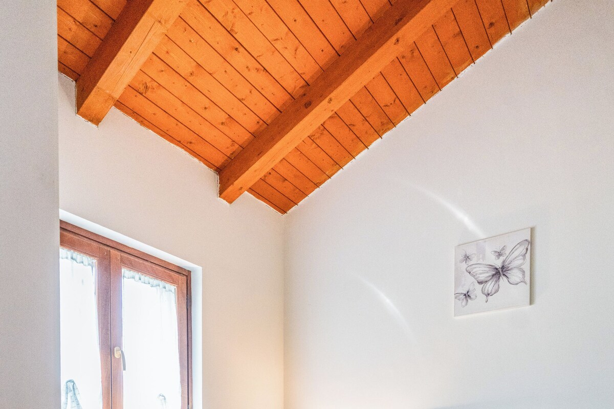 Une chambre à coucher avec un lit, une fenêtre, une table de chevet et une lampe fixée au mur.