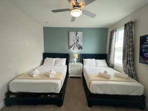 A hotel room with two beds, a ceiling fan, a nightstand with a lamp, and a painting on the wall. - 11BR near Disney | Pool, spa & movie theater (Kissimmee)