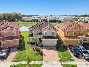 A residential area with houses, a driveway, and a body of water in the background. - 8BR near Disney | Private pool, spa & lake view (Kissimmee)