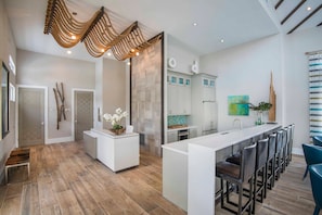 A modern kitchen with a central island, bar seating, and a unique ceiling design. - 8BR near Disney | Private pool, spa & lake view (Kissimmee)