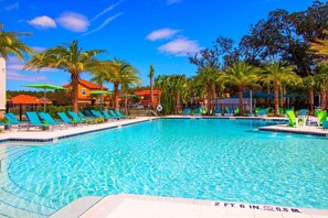 A clear blue swimming pool with lounge chairs and palm trees. - 8BR near Disney | Private pool, spa & lake view (Kissimmee)