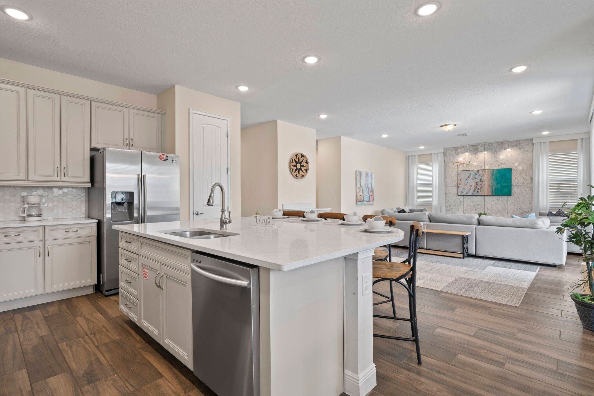 A modern kitchen with a central island, stainless steel appliances, and a dining area with a sofa and chairs.