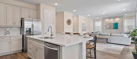 A modern kitchen with a central island, stainless steel appliances, and a dining area with a sofa and chairs.