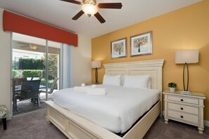 A bedroom with a bed, a nightstand, a ceiling fan, and a view of the outdoors. - 11BR near Disney | Private pool and spa (Kissimmee)