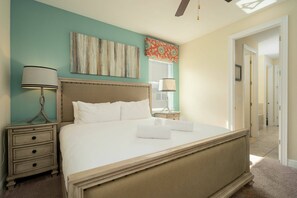 A bedroom with a large bed, bedside tables, a ceiling fan, and artwork on the walls. - 11BR near Disney | Private pool and spa (Kissimmee)