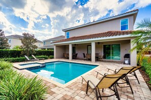 Ein Wohnhaus mit Swimmingpool, Terrassenmöbeln und einer überdachten Außenbereitschaft.
