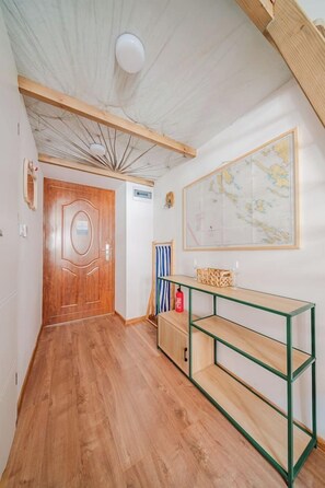Ein Korridor mit einer Holztür, einer Karte an der Wand und einem grünen Metallregal.