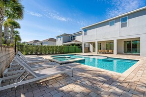 A modern residential building with a swimming pool, outdoor seating, and a well-maintained garden. - 10BR near Disney | Private pool, spa & game room (Kissimmee)