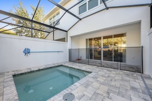 A swimming pool with a glass enclosure, a patio area with a view of the interior, and a covered outdoor space with a glass door. - 3BR townhouse near Disney | Pool & Mickey room (Clermont)