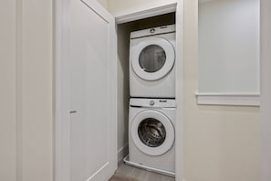 A laundry room with two stacked washing machines, a door, and a wall-mounted control panel. - 3BR townhouse near Disney | Pool & Mickey room (Clermont)