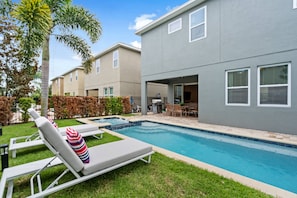 A residential pool area with lounge chairs and a barbecue grill. - 6BR near Disney | Private pool, spa & loft (Kissimmee)
