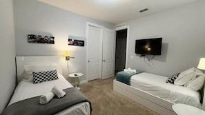 A hotel room with two beds, a television, a door, and a small table. - 6BR near Disney | Private pool, spa & loft (Kissimmee)