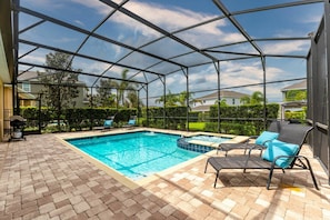 A covered outdoor swimming pool with lounge chairs and a grill. - 6BR near Disney | Private pool, spa & game room (Kissimmee)