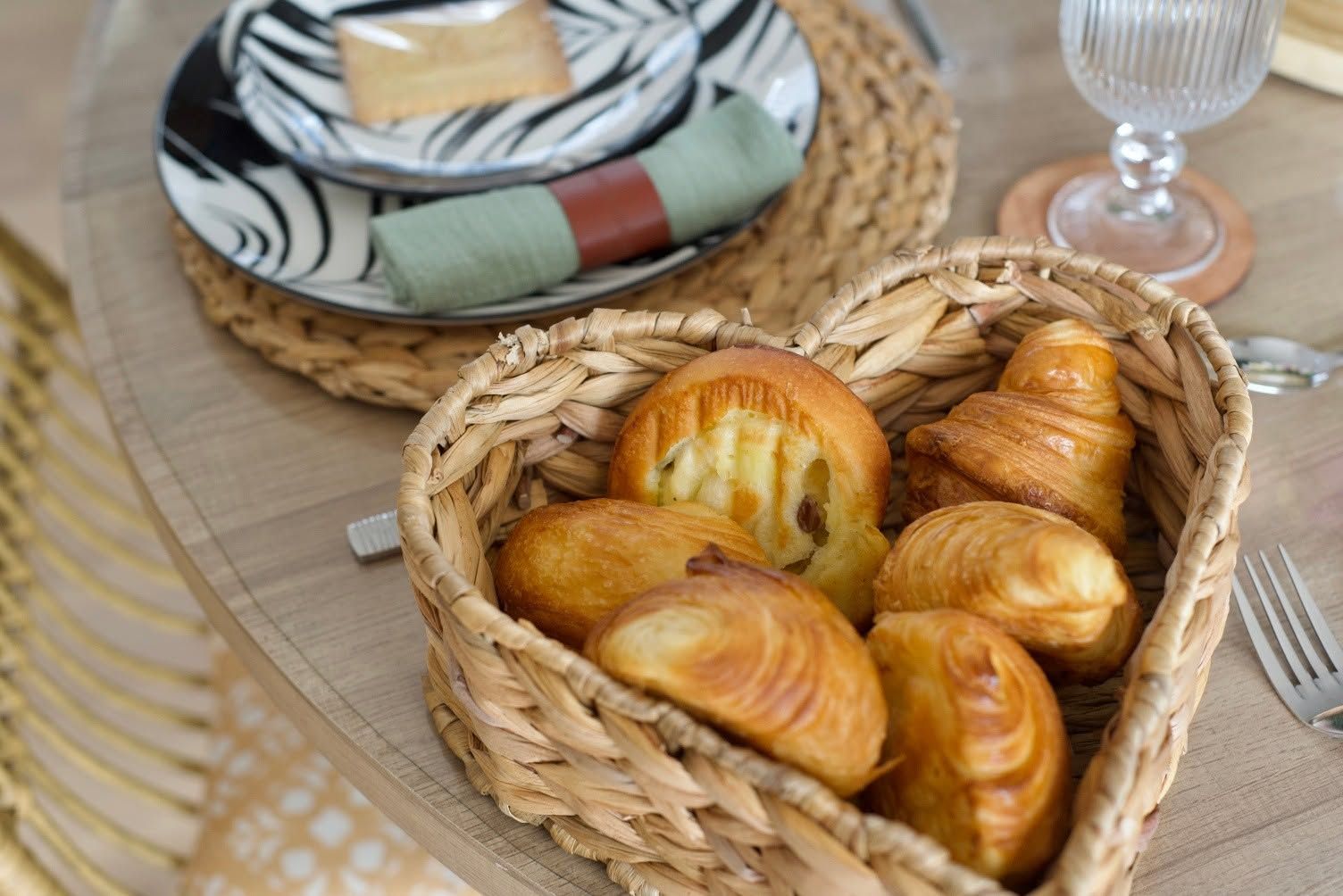 A wicker basket filled with croissants on a table.