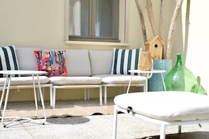 A sunlit outdoor seating area with a sofa, two chairs, and a small table.