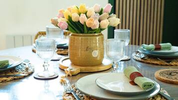Una mesa de comedor dispuesta con platos, cubiertos y un jarrón de flores.