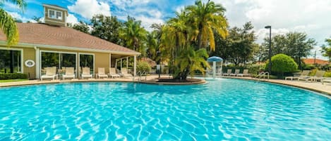 Una piscina con sillas de descanso y palmeras.