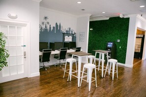A modern workspace with multiple computer stations, white stools, and a green wall mural. - 3BR townhome near Disney | Resort pool access (Kissimmee)