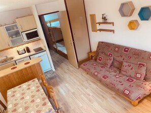 A compact living space with a kitchenette, a sofa, and a dining area. - Vrbo Property (Tignes)