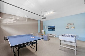A recreational room with a ping pong table, foosball table, and a projector screen. - 8BR near Disney | Pool, spa & game room (Kissimmee)
