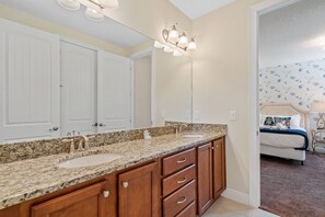A bathroom with a double sink vanity, a large mirror, and a wall-mounted light fixture. - 8BR near Disney | Pool, spa & game room (Kissimmee)