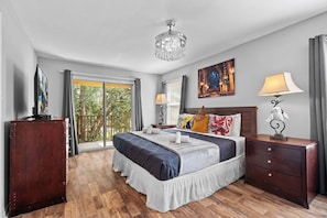 Quarto de hotel com cama, mesas de cabeceira, abajur, pintura e vista pela janela.