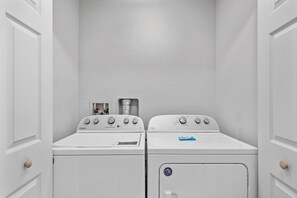 A laundry room with two stacked washers and dryers, a water heater, and a control panel. - 4BR themed townhome near Disney | Lazy river (Davenport)