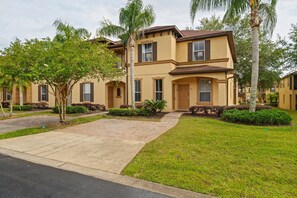 A two-story residential building with a brick driveway and a well-maintained lawn. - 4BR themed townhome near Disney | Lazy river (Davenport)
