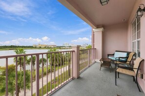 A balcony with a view of a river, palm trees, and buildings in the distance. - Vista Cay 4BR Condo • Lake View • Near Universal (Orlando)