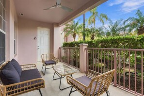 A balcony with wicker furniture, a glass table, and a view of palm trees. - Vista Cay 3BR Condo • King Suite • Near Universal (Orlando)
